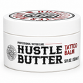 A white plastic jar of Hustle Butter Tattoo Balm with a white lid, featuring black and red text on a clean white background.